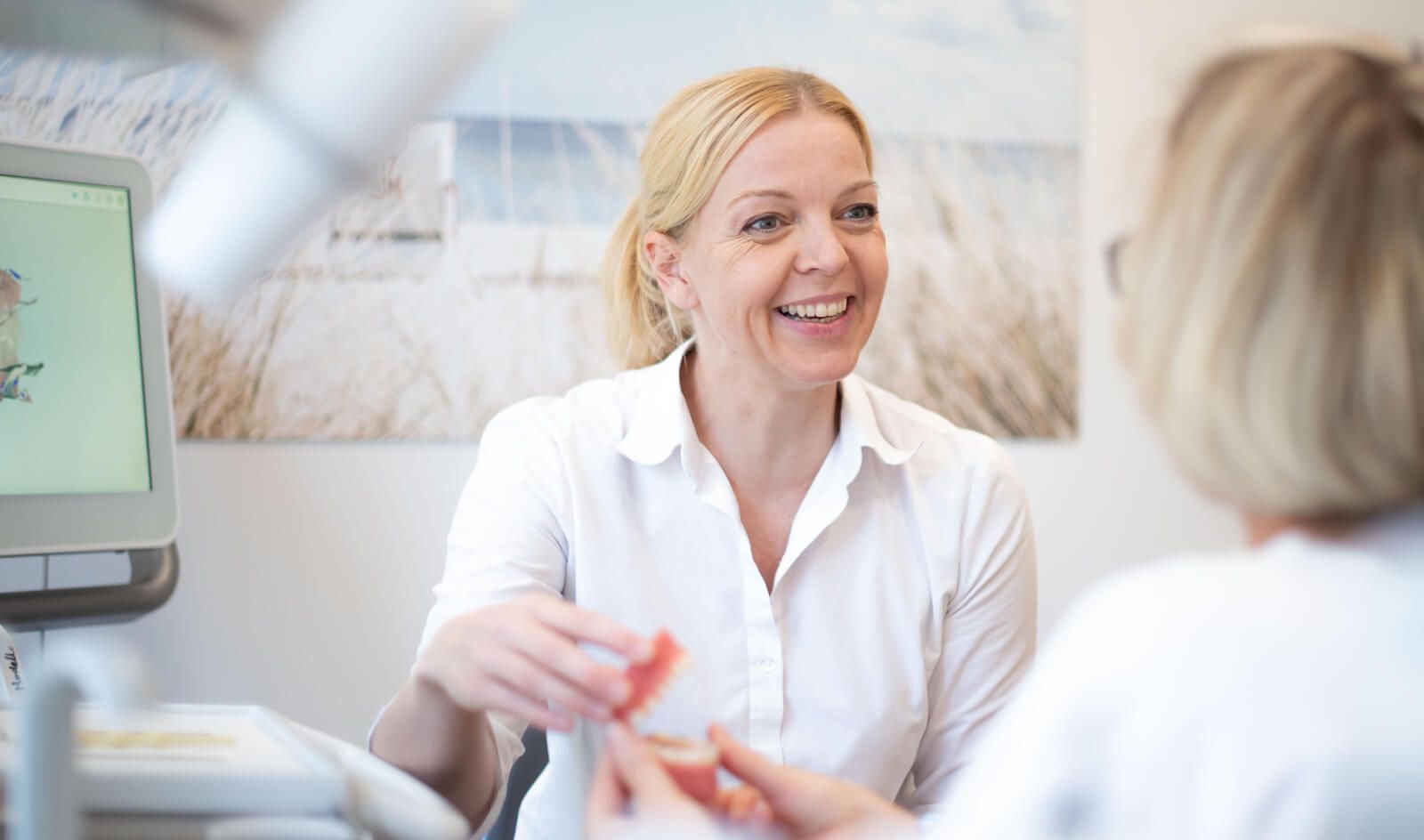 Dr. Jana Nordmann zeigt einer Patientin verschiedene Zahnspangen
